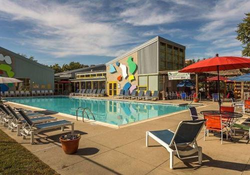 An outdoor pool with lounge chairs and umbrellas at Enclaves at 封隔器公园 apartments for rent